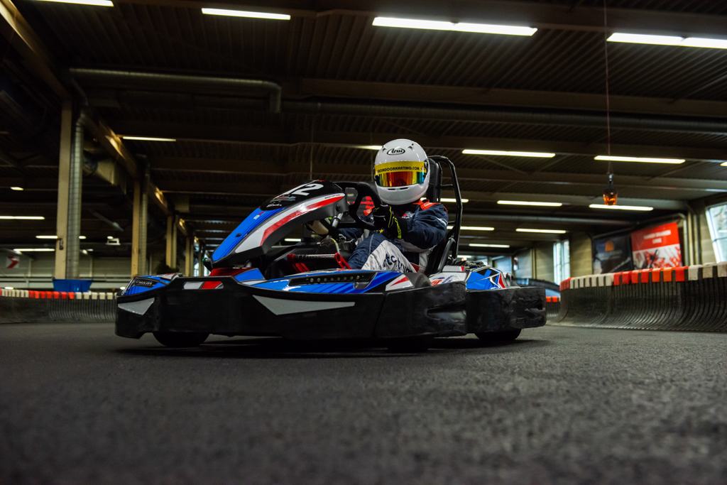 Close-up van een rijder in een kart, gefocust op de actie en helm.