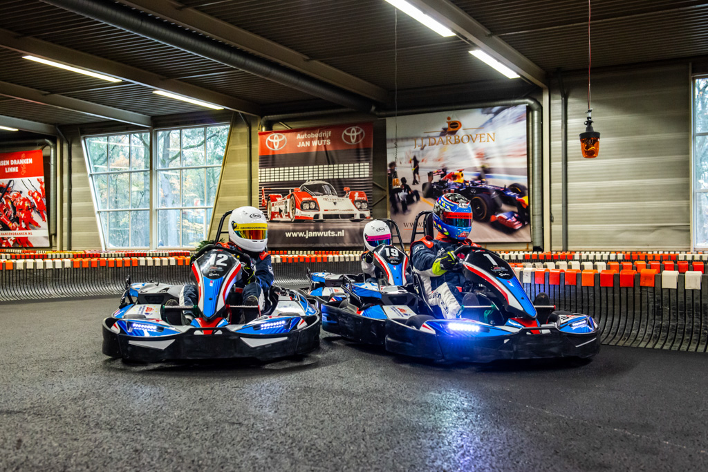 Sfeervolle actiefoto van een karter in een bocht op de indoorbaan met neonverlichting.