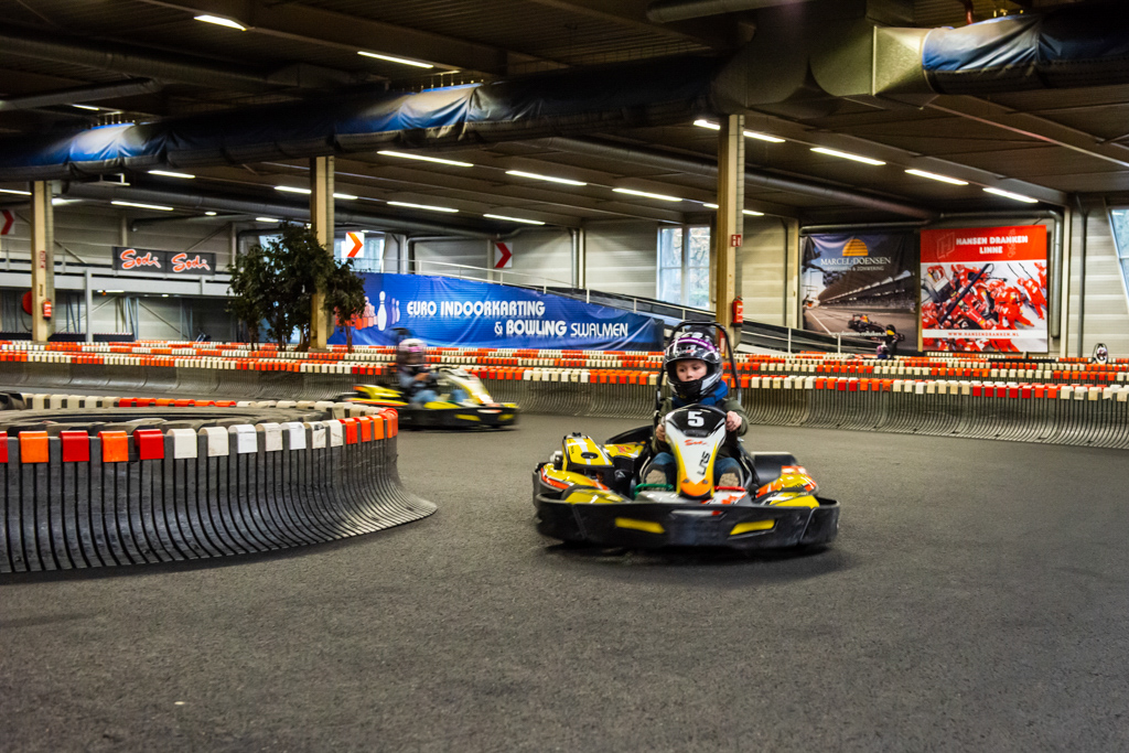 Overzichtsfoto van de kartbaan met meerdere karts in actie onder sfeervolle verlichting.